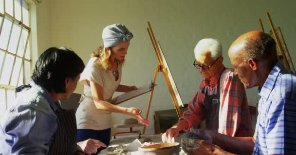 Женщина помогает художникам в гончарном деле — стоковое видео