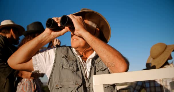 Amigos mirando a través de prismáticos durante las vacaciones de safari 4k — Vídeos de Stock