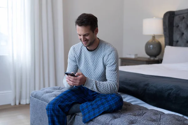 Uomo che utilizza il telefono cellulare in camera da letto — Foto Stock