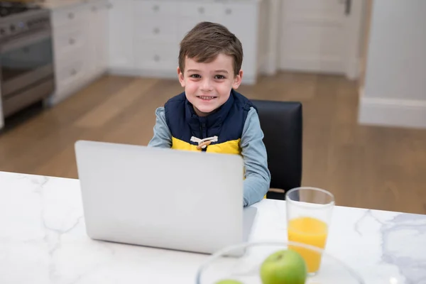 Boy using laptop in kitchen — Stock Photo, Image