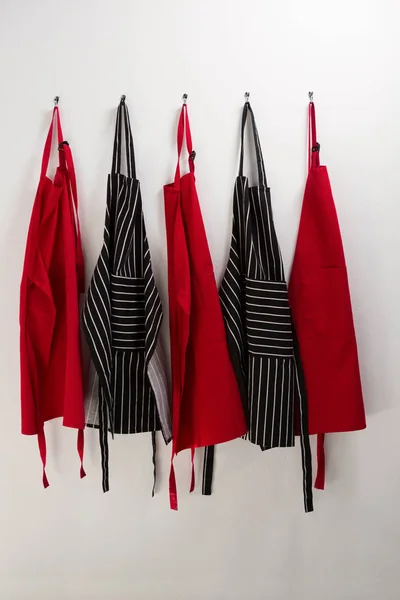 Various aprons hanging on hook — Stock Photo, Image