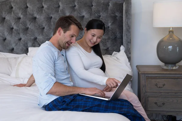 Couple using laptop in bedroom — Stock Photo, Image