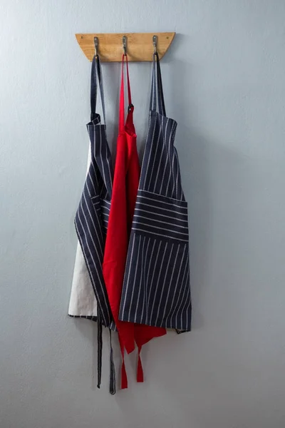 Various aprons hanging on hook — Stock Photo, Image