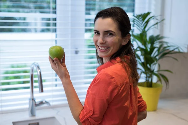 Donna che tiene una mela verde in cucina — Foto Stock
