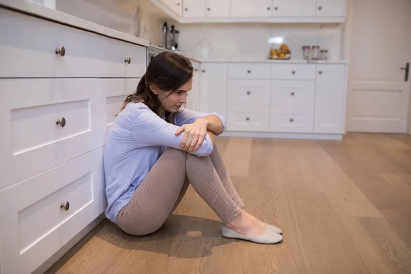 Worried woman sitting in kitchen — Stock Photo, Image