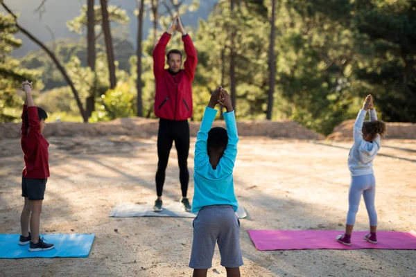 Coachen van meewerkende kinderen in het beoefenen van yoga — Stockfoto