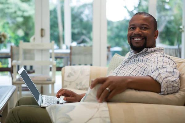 Homem usando laptop no sofá — Fotografia de Stock