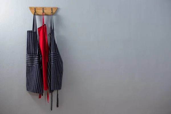 Various aprons hanging on hook — Stock Photo, Image