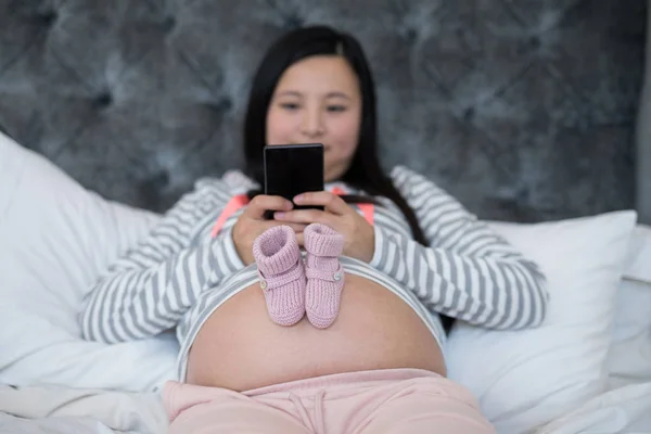 Baby socks on pregnant woman stomach — Stock Photo, Image