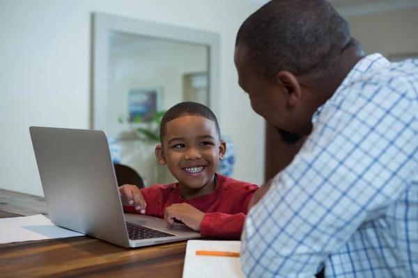 Padre e figlio utilizzando il computer portatile in soggiorno — Foto Stock