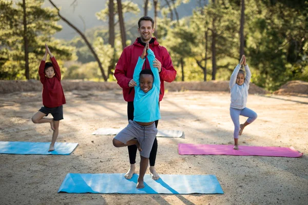 Coachen van meewerkende kinderen in het beoefenen van yoga — Stockfoto