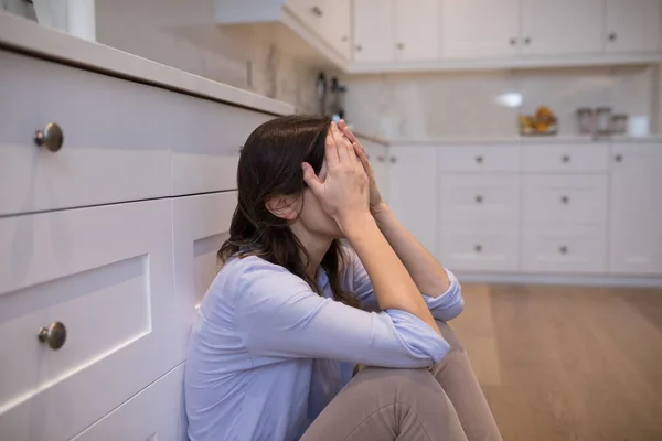 Worried woman sitting in kitchen — Stock Photo, Image