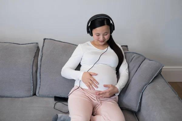 Kobieta w ciąży, słuchania muzyki na słuchawkach — Zdjęcie stockowe