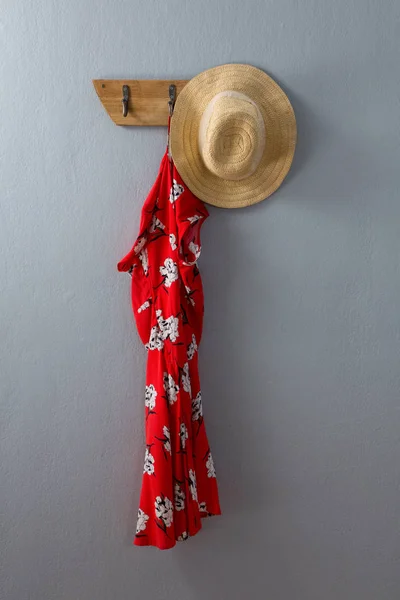 Červené šaty a čepice visící na háčku — Stock fotografie