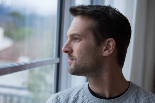 Thoughtful man looking through window — Stock Photo, Image