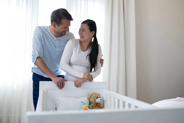 Happy couple standing near cot — Stock Photo, Image