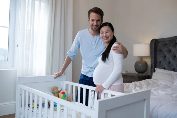 Happy couple standing near cot — Stock Photo, Image