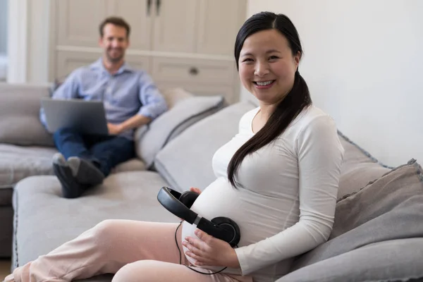 Donna incinta Posizionamento cuffie sullo stomaco — Foto Stock