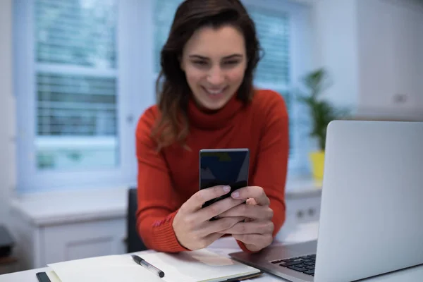 Kvinna med mobiltelefon på skrivbord — Stockfoto