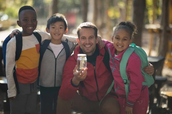 Enseignant et enfants examinant la plante en pot — Photo