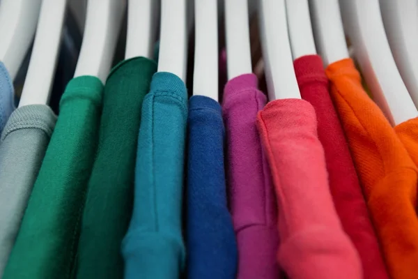 Различные футболки, висящие на вешалке — стоковое фото