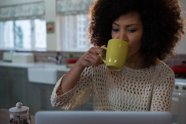 Donna che prende il caffè mentre usa il computer portatile — Foto Stock