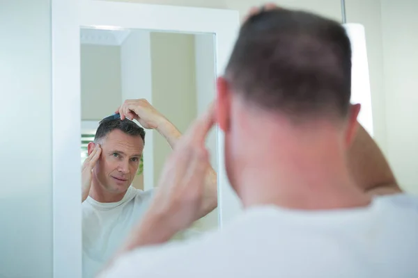 Hombre peinándose el pelo en el baño — Foto de Stock