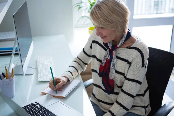 Vrouw schrijven in organisator terwijl het gebruiken van laptop — Stockfoto