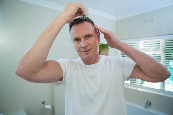 Hombre peinándose el pelo en el baño — Foto de Stock