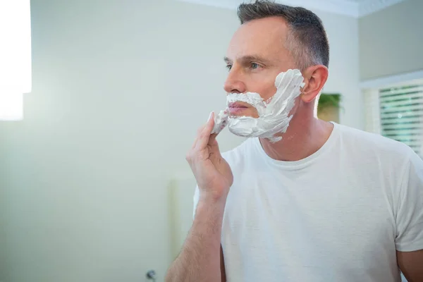 Uomo che si applica schiuma da barba sul viso — Foto Stock
