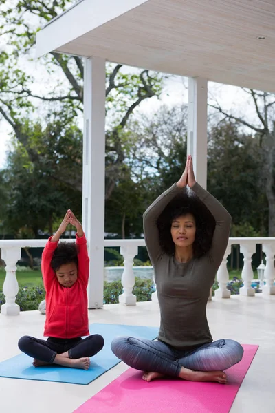 Madre e figlia meditando insieme in veranda — Foto Stock