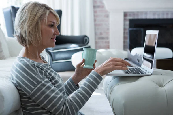 Woman using laptop in living room — Stock Photo, Image