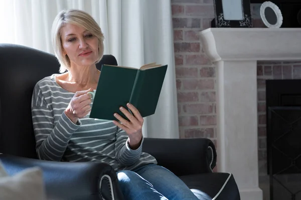 Mujer leyendo libro mientras toma café — Foto de Stock