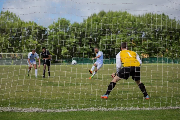 Jogador de futebol chutando bola em direção ao posto de gol — Fotografia de Stock