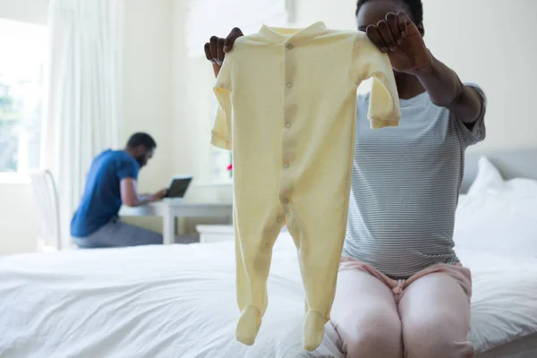 Pregnant woman holding baby clothes — Stock Photo, Image