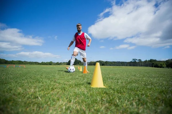Jogador de futebol driblando através de cones — Fotografia de Stock