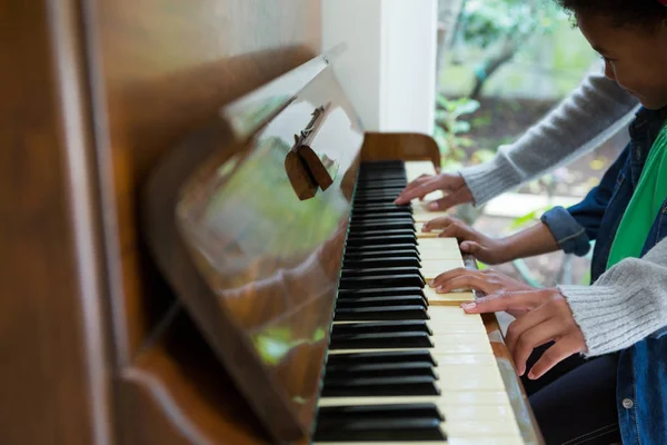 Madre ayudando a su hija a tocar el piano — Foto de Stock