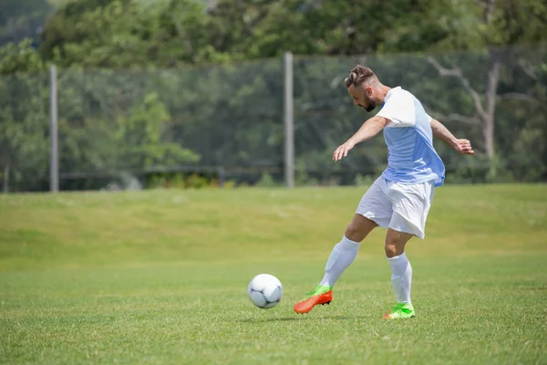 Jugador de fútbol pateando el fútbol — Foto de Stock