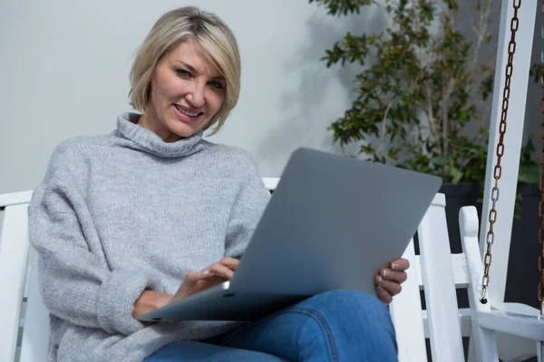 Woman using laptop in porch — Stock Photo, Image