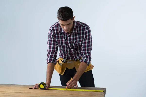 Arquiteto masculino medindo prancha de madeira — Fotografia de Stock
