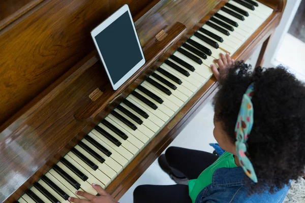 Flicka spela piano med digital tablett — Stockfoto