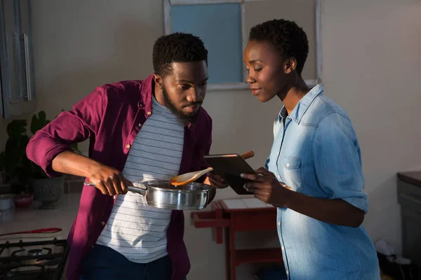 Pareja usando tableta mientras cocina — Foto de Stock