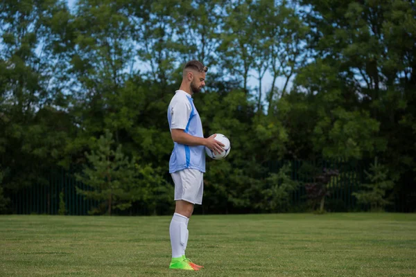 Jogador de futebol segurando futebol no chão — Fotografia de Stock