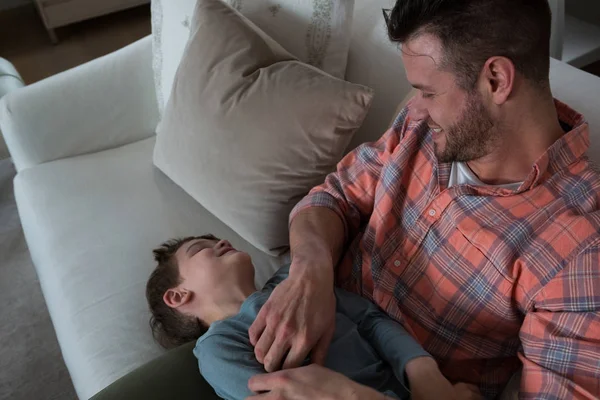 Vater kitzelt seinen Sohn im Wohnzimmer — Stockfoto