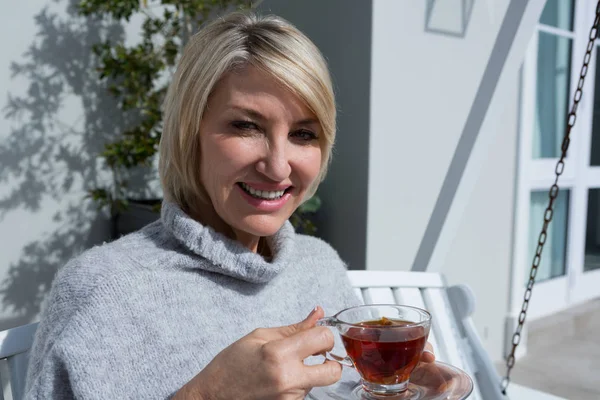 Mujer tomando té de limón en el porche — Foto de Stock