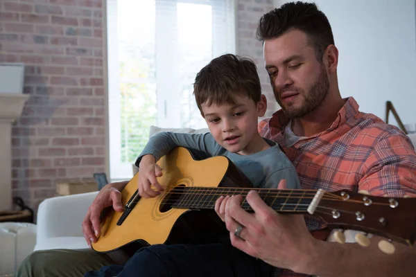 Vater hilft seinem Sohn beim Gitarrespielen — Stockfoto