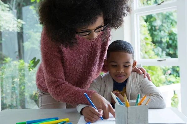Mutter hilft ihrem Sohn bei den Hausaufgaben — Stockfoto