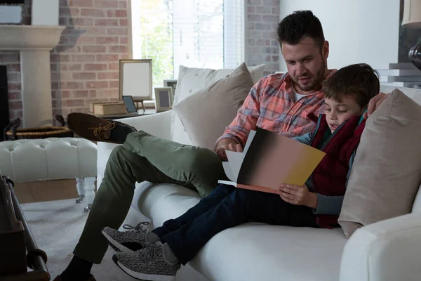 Father ans son reading book in living room — Stock Photo, Image