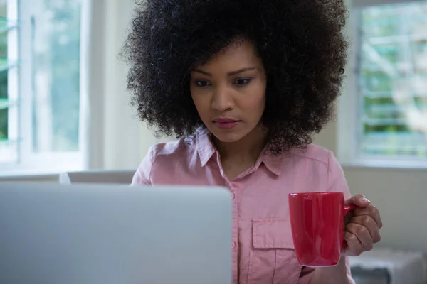 Frau benutzt Laptop beim Kaffeetrinken — Stockfoto