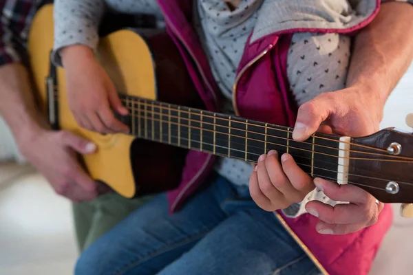 Отец помогает дочери играть на гитаре. — стоковое фото